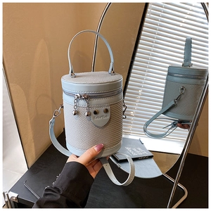 Dettaglio della borsa a secchiello azzurra intrecciata con texture pregiata e zip in metallo