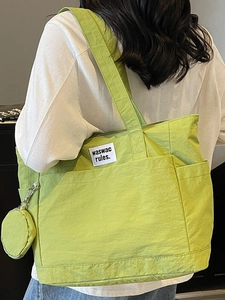 Green canvas tote bag with small pouch and waswac rules text label shown on model