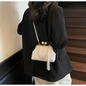 Detailed view of white jacquard bag with pearl chain and tassel on model's back