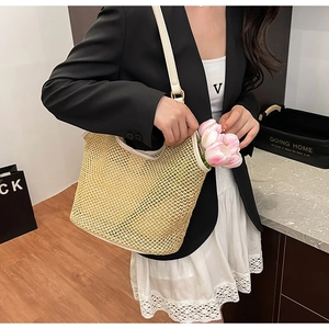 Detail of hand-woven straw tote bag featuring white faux leather straps and mesh texture