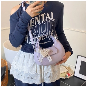 Détail du sac lavande avec texture litchi et pendentif de nœud en perles élégant