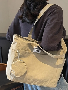 Minimalist large khaki tote bag with a small round pouch shown on a fashion model