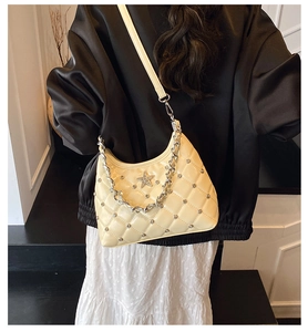 Detail of quilted beige bag with star metal logo and silver chain on model