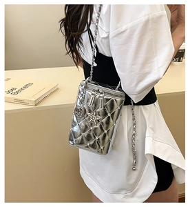 Detail of silver quilted crossbody bag with star charm and metallic chain strap