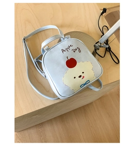 Détail du sac à dos bleu clair Apple Dog avec motif chiot posé sur une table en bois