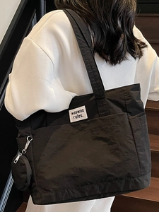 Minimalist black canvas tote bag for women with a mini coin purse and white text label