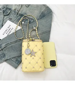Detail of yellow quilted mini bag with silver chain, rhinestones and charms for size reference