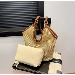 Detail view of woven straw tote bag with brown leather trim and canvas inner pouch