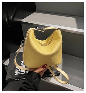 Detail of yellow pebbled leather handbag with silver zipper and embossed logo