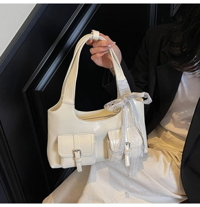 Dettaglio della borsa tote bianco crema con fiocco in pizzo e finitura in ecopelle lucida