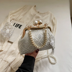 Close-up of vintage embroidery evening bag with large pearl clasp and white tassel details