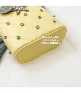 Detailed close-up of yellow quilted leather bag with rhinestone studs and star pendant