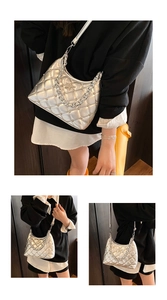 Detail of silver quilted handbag featuring metallic star logo and thick chain strap