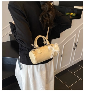 Detailed back view of a beige cylinder bag featuring elegant lace bows and pearl charms