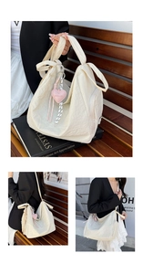 Détail d'un sac cabas crème texturé avec pendentif cœur et poche latérale zippée