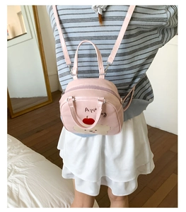 Mini sac à dos rose motif chiot et pomme porté par un mannequin dans un décor maison