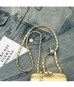 Detail of yellow quilted leather bag with adjustable silver ball chain on denim jacket