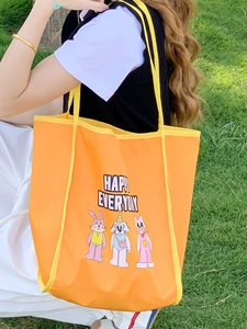 Orange tote bag with cartoon animal embroidery and Happy Everyday text on grass