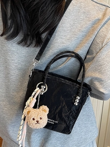 Minimalist black bucket bag with crinkle texture and cute teddy bear pendant charm