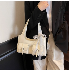 Dettaglio della borsa tote bianco sporco con tasche cargo e ciondolo a fiocco a scacchi blu