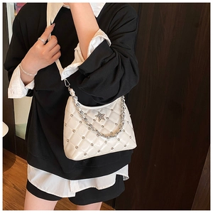 Detail of white quilted bag with silver rivets, star emblem and metal chain strap