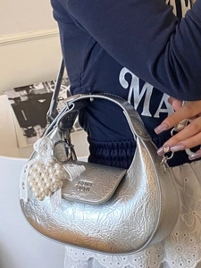 Sac bandoulière argenté forme demi-lune avec nœud en dentelle et perles sur un mannequin