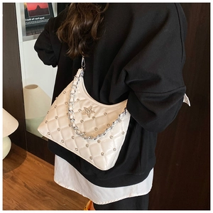 Close-up of white quilted shoulder bag with silver star studs and metal chain strap