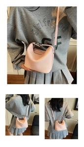 Detail of pink pebbled leather handbag with MERPAI logo and matching shoulder strap