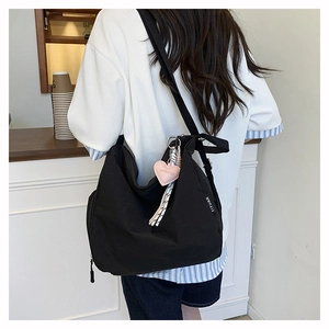 Détail du sac fourre-tout noir en toile avec pendentif coeur rose et étiquette YIYUAN