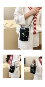 Detailed view of black quilted bucket bag with star diamond studs and silver chain strap