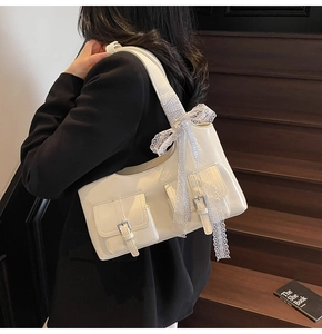 Dettaglio di una borsa tote in vernice bianca con fiocchi su una scala di legno