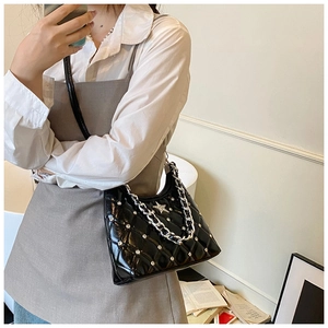 Detail of black quilted patent shoulder bag with silver star rivets and chunky chain strap