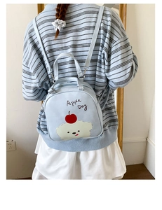 Mini sac à dos bleu clair avec dessin de chien pomme porté par un mannequin féminin
