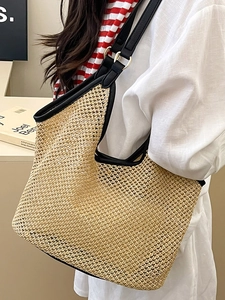 Large beige woven tote bag with black leather straps and gold metal rings for women