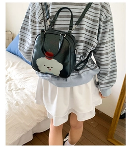 Détail d'un mini sac à dos noir avec motif de chien et texture enduite brillante