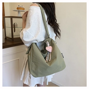 Détail d'un sac cabas vert olive avec breloque cœur et étiquette de marque en nylon