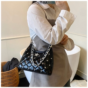 Close-up of black quilted shoulder bag with silver star emblem and sparkling rhinestones