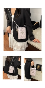 Close-up of pink quilted cylindrical bag with silver studs and star detail and chain strap