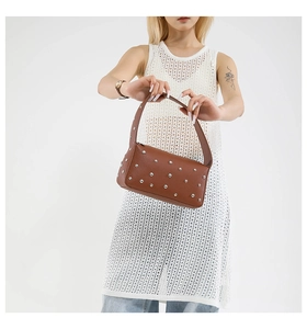 Detail of brown litchi pattern leather bag with silver rivets and wide strap on model