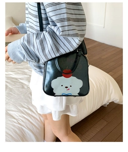Détail d'un sac bandoulière en cuir noir avec imprimé mignon de chien et de cerise