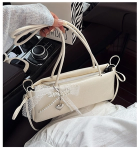 Détail du sac crème avec nœud en dentelle et pendentif cœur en perles dans une voiture