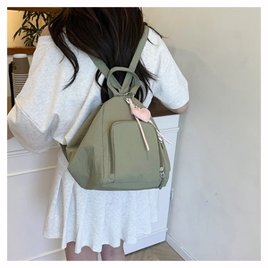 Détail d'un sac à dos léger en nylon vert pois avec un pendentif cœur rose sur l'épaule