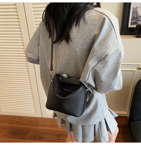 Detail of black lychee grain leather bucket bag featuring silver metal hooks and shoulder strap