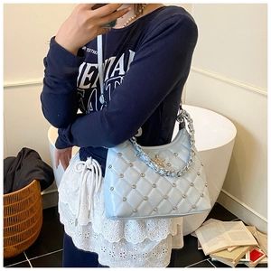 Detail of light blue quilted crossbody bag with silver studs and star charm