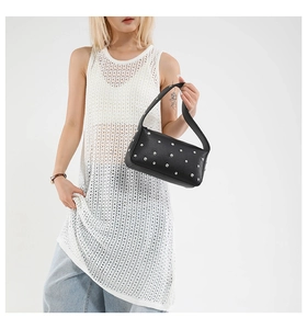 Detail view of black lychee leather hobo bag with silver rivets worn by a model