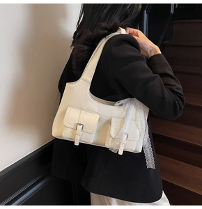 Dettaglio borsa tote in pelle bianca con fiocco in pizzo sulla spalla di un modello