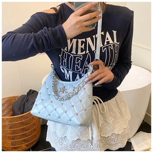 Close-up of light blue quilted bag featuring silver studs and star emblem detail