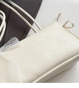 Détail de la texture léopard gaufrée crème et du nœud en dentelle blanche sur le sac