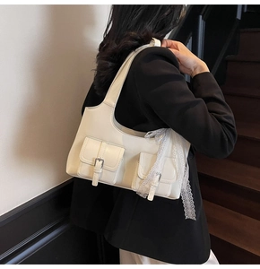 Modella che indossa borsa sottobraccio bianca con lacci decorativi e fibbie in argento