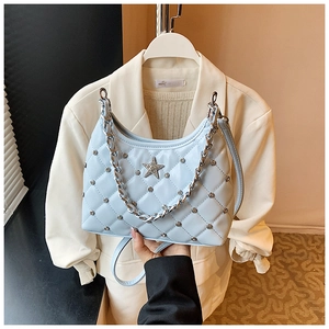 Detail of light blue quilted leather handbag featuring silver chain and metal star emblem